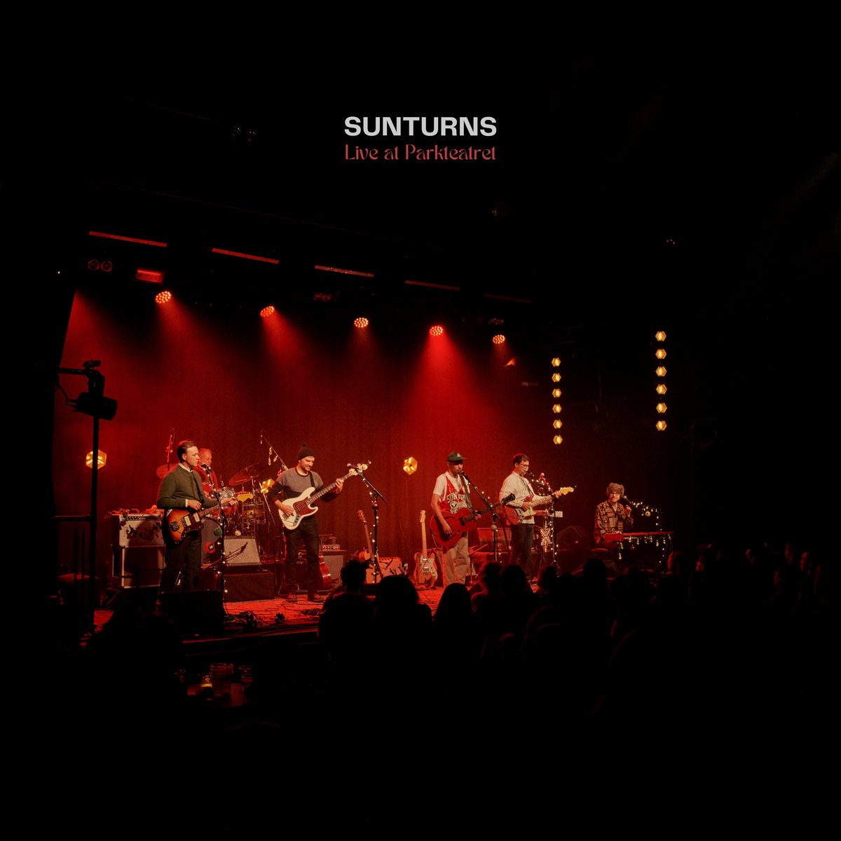 a band standing on stage bathed in red light.
